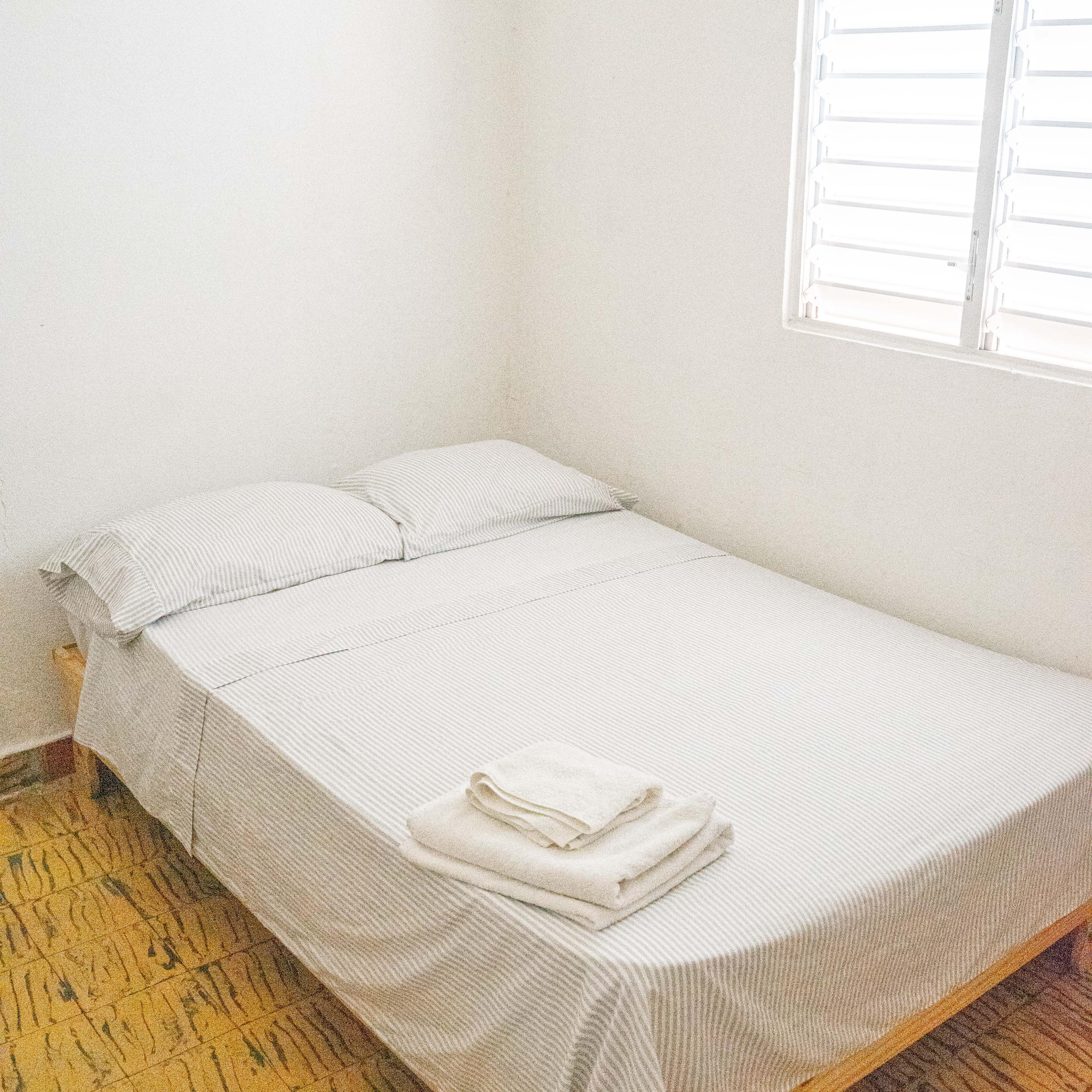 Cama doble preparada con toallas en una habitación de Gato Colonial